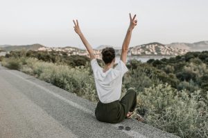 woman sitting on the road making a peace sign